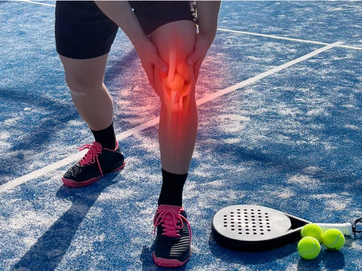 Athlete holding knee in pain on tennis court from ACL injury.